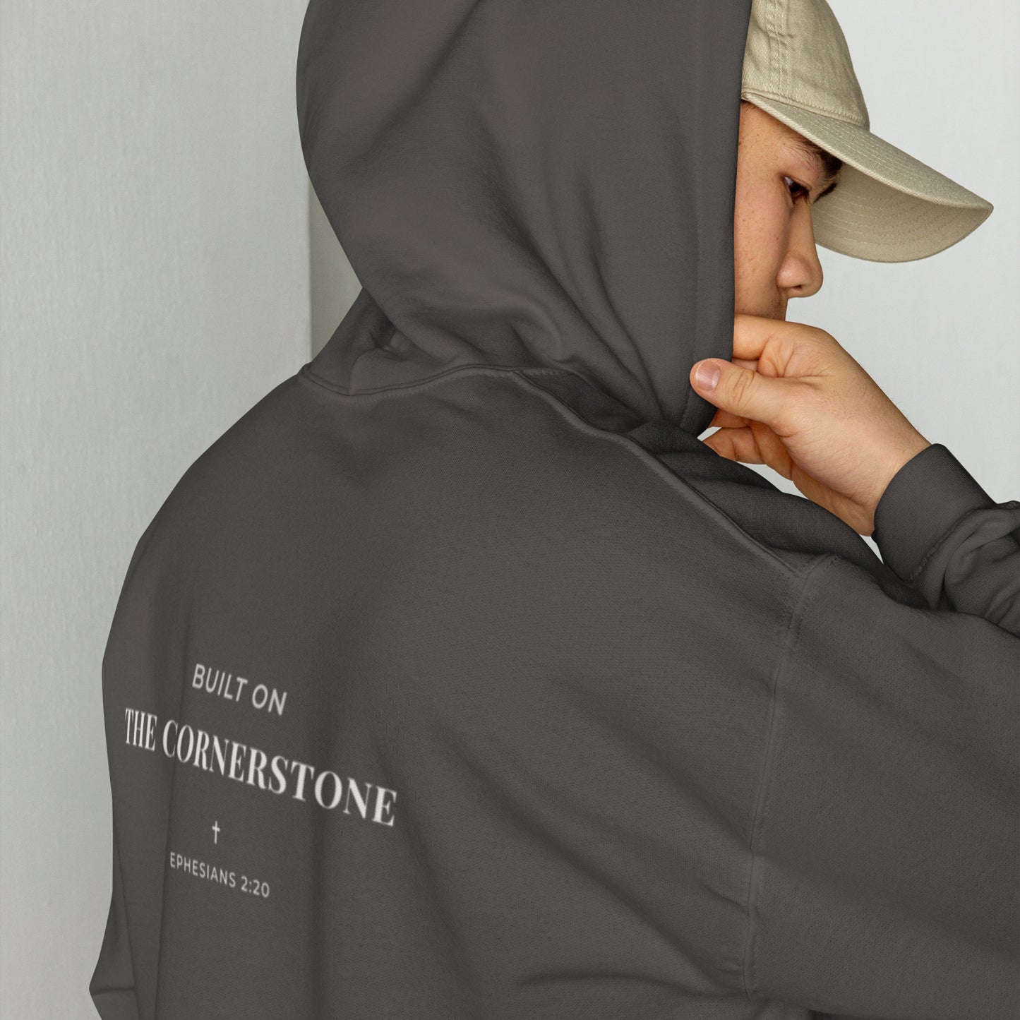 Person wearing a Cornerstone Wear unisex dark grey hoodie with text, standing against a plain background