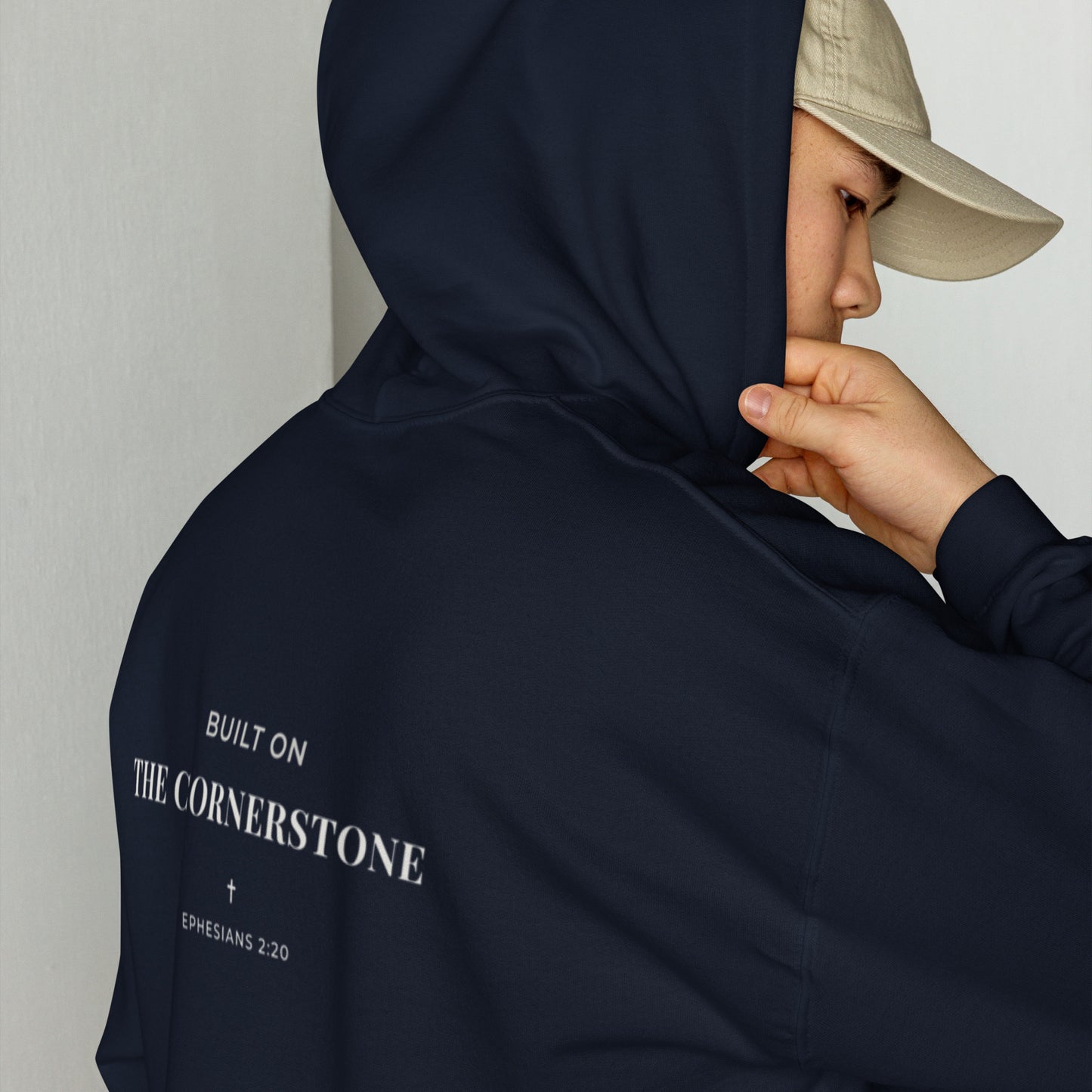 Person wearing a Cornerstone Wear unisex navy hoodie with text, standing against a plain background