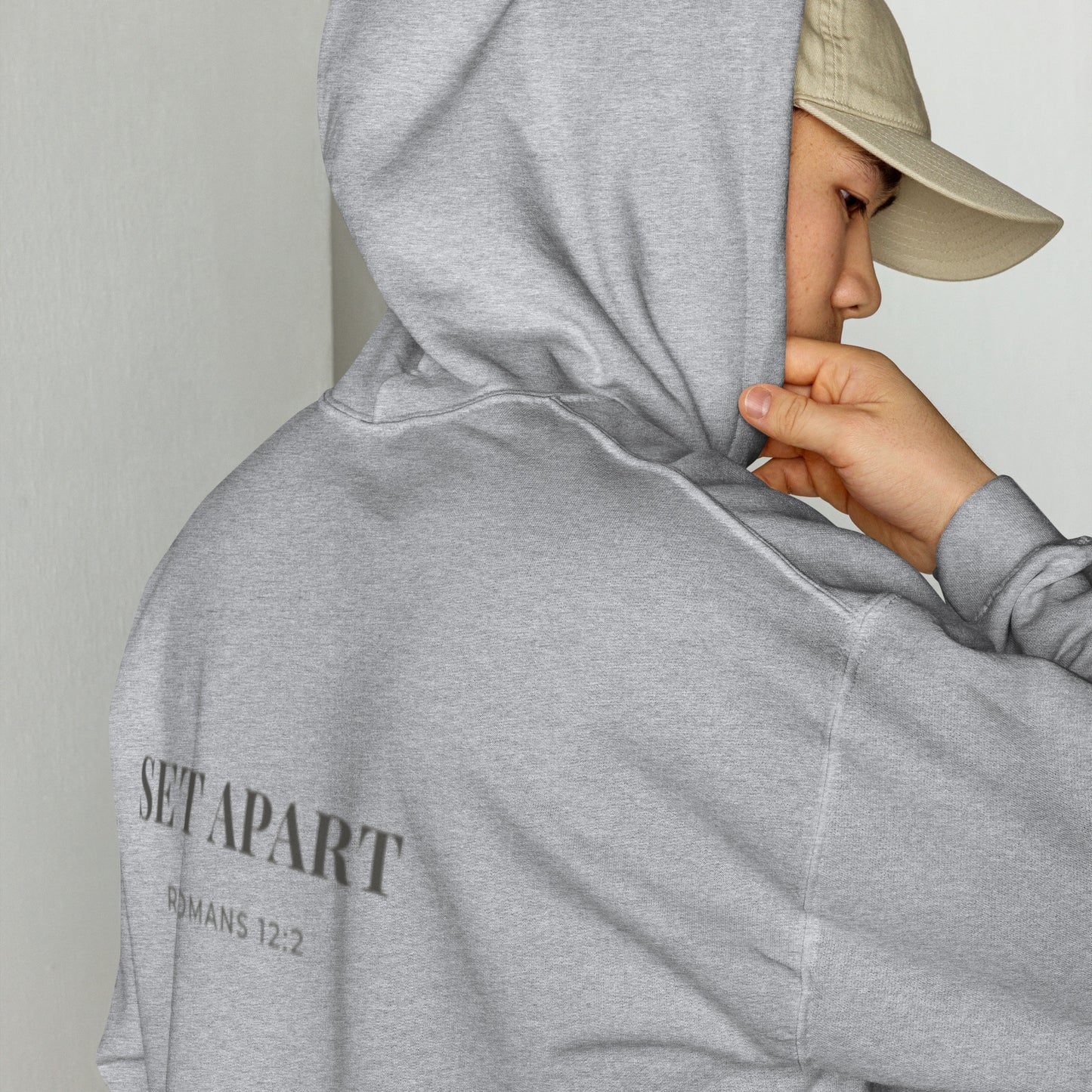 Person wearing a Cornerstone Wear unisex grey hoodie with text, standing against a plain background