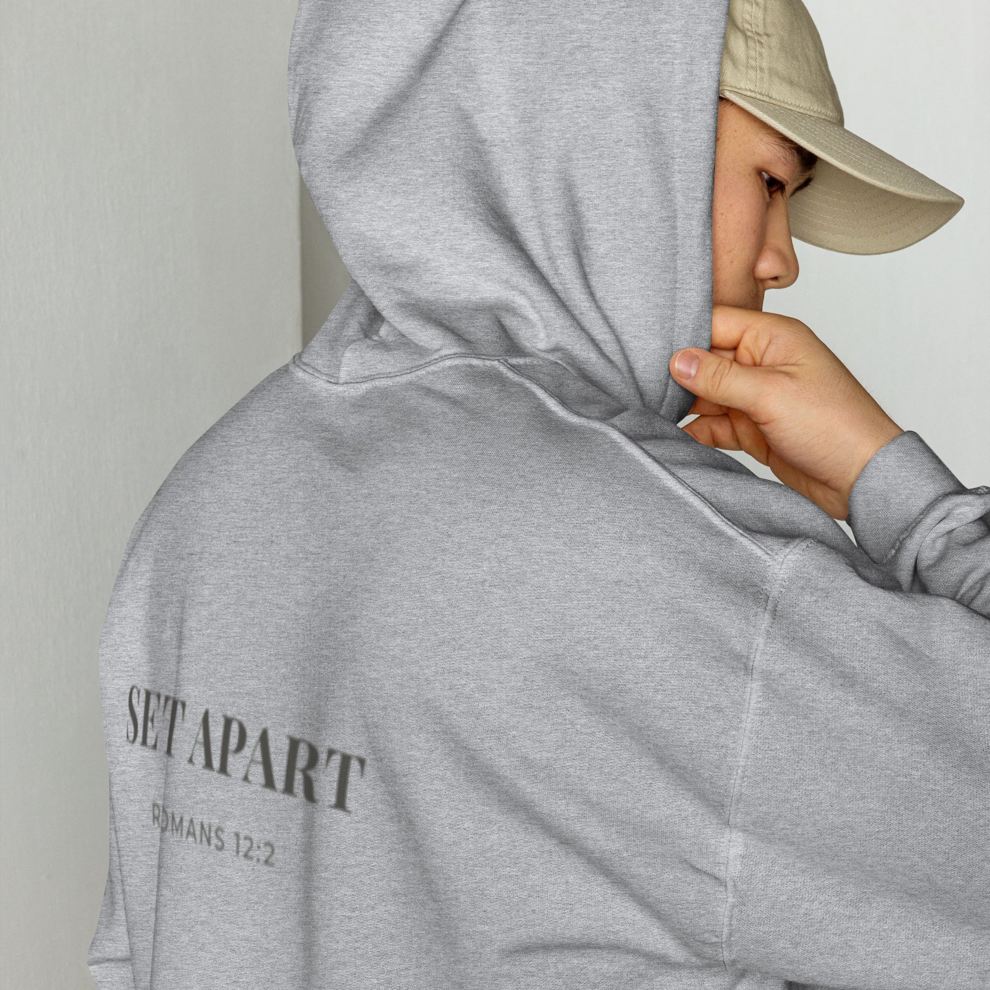 Person wearing a Cornerstone Wear unisex grey hoodie with text, standing against a plain background